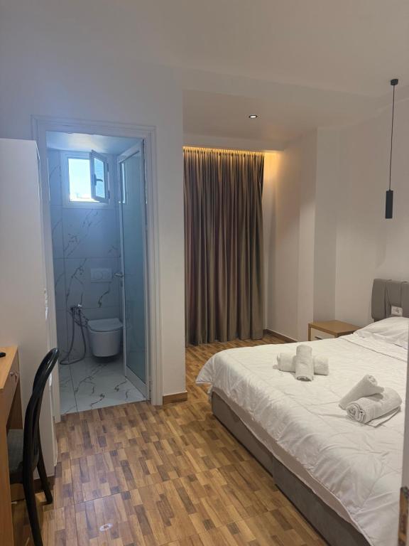 a bedroom with a bed and a bathroom with a toilet at Blue Pines Villa in Vlorë