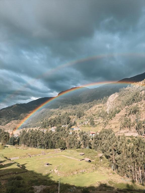 a rainbow in the sky over a field with trees at Mama Raywa in Chavín de Huantar