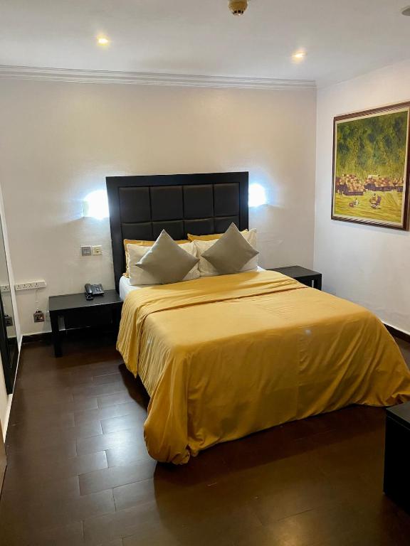a bedroom with a large bed with a yellow bedspread at Stylish Modern Elegance Deluxe Suite in Lagos