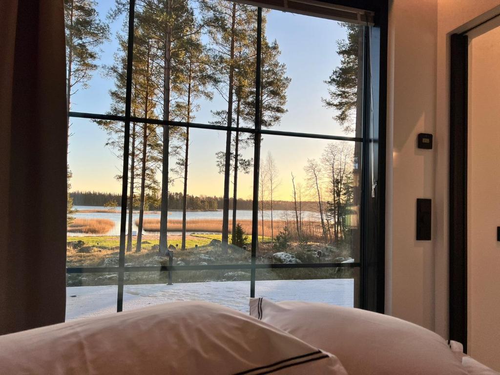 een slaapkamer met een groot raam met uitzicht op een meer bij New Seaside Villa with Beach Sauna and Panoramic Views in Porvoo