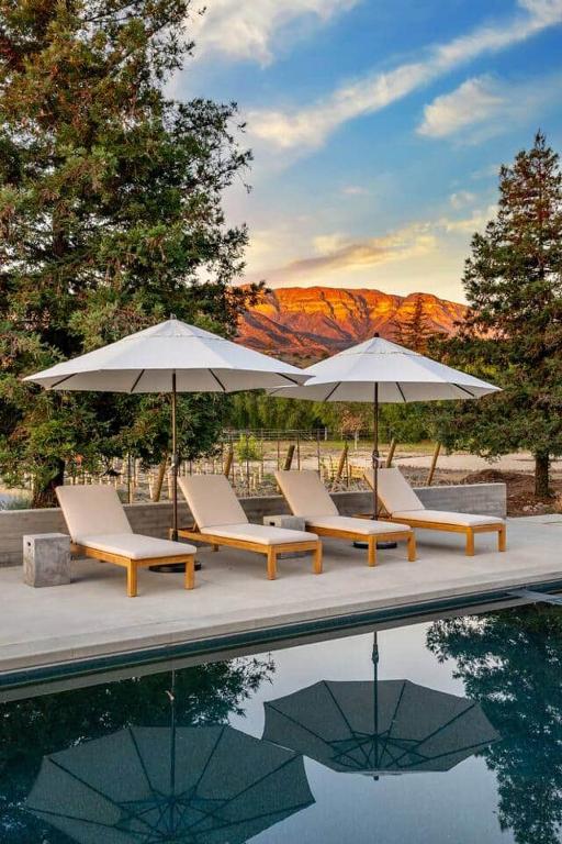 a group of chairs and umbrellas next to a pool at Ojai Valley - Pool and Pickle Ball in Ojai