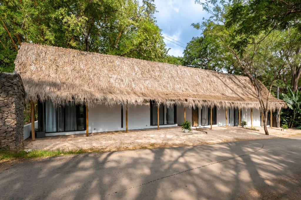 a house with a thatched roof and a street at 5 Lofts En La Paraiso in Playa Grande
