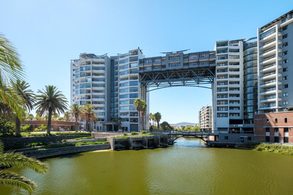 a bridge over a river with palm trees and buildings at Belina - Knightsbridge Prestige Suite in Cape Town
