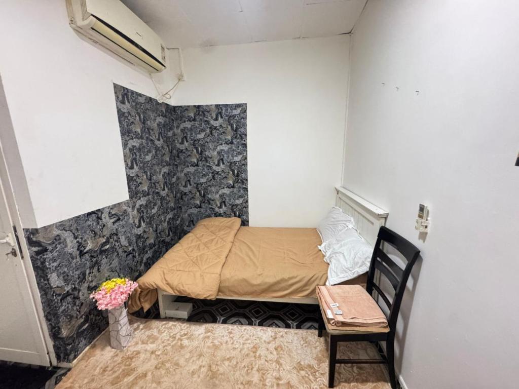 Four Star Royel Real Estate في أبوظبي: غرفة نوم صغيرة بها سرير وكرسي