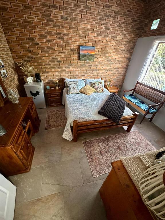 a bedroom with a bed and a brick wall at Prag Overnight Room in Orania