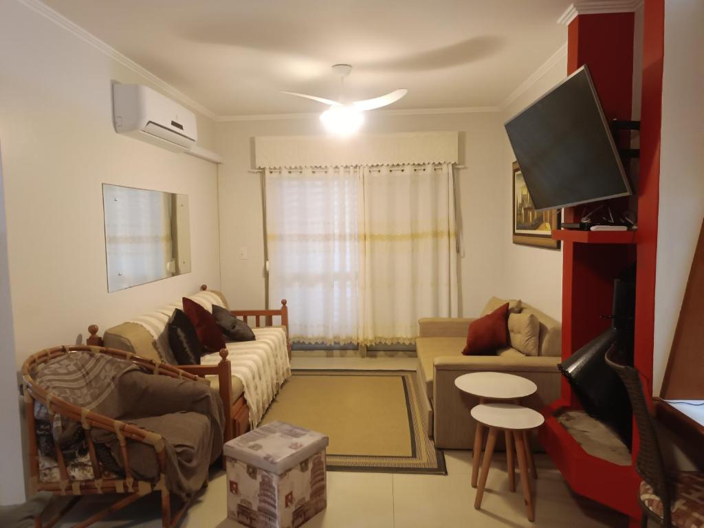een woonkamer met een bank en een tv bij Apartamento Capão Novo in Capão da Canoa