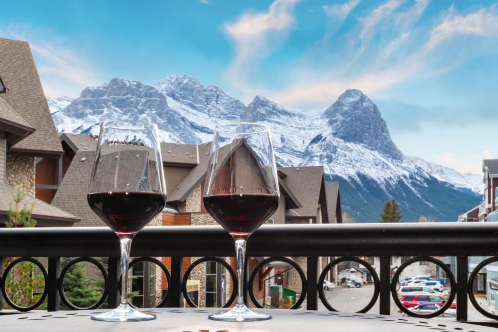 キャンモアにあるRenovated Haven in Rockies with Hot Tub and Poolの山を眺めながらバルコニーに座ってワインを2杯飲む