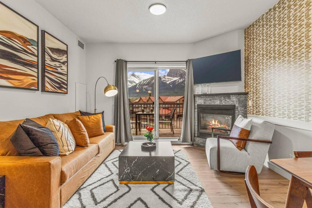 een woonkamer met een bank en een open haard bij Rockies Getaway Condo With Mountain View in Canmore