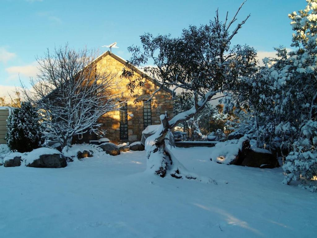 een met sneeuw bedekte tuin voor een kerk bij Bush Rock Touchdown Cottages in Jindabyne