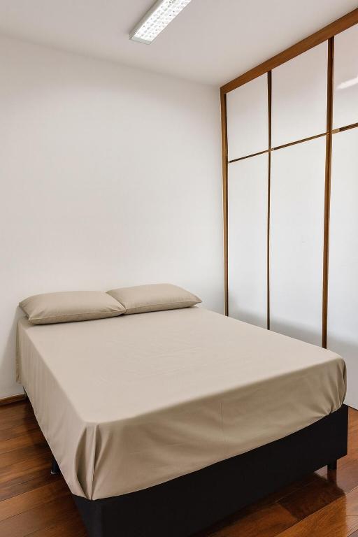 Studio Privativo 3 min Centro para 4 pessoas com 2 quartos ar condicionado في أبرلانديا: سرير في غرفة بجدار أبيض