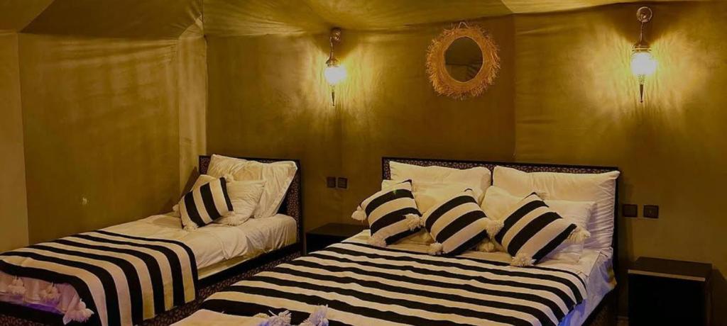 een slaapkamer met 2 bedden en zwarte en witte kussens bij Merzouga camping in Merzouga