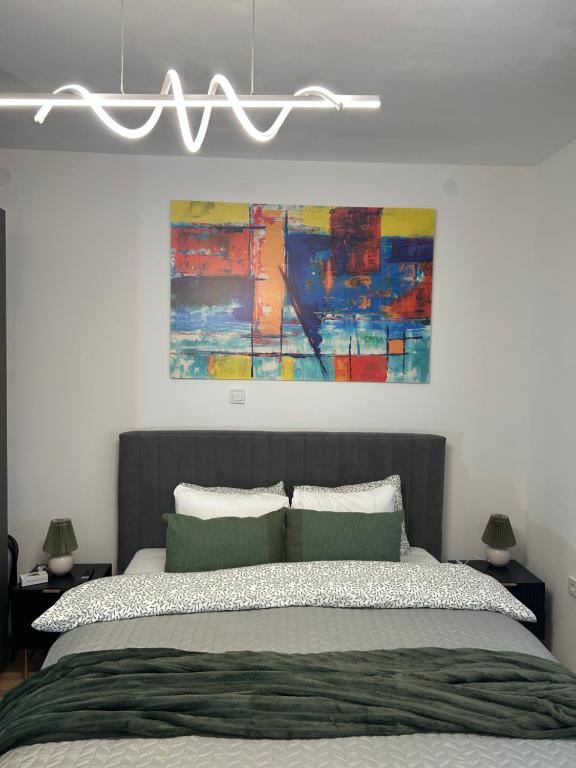 a bedroom with a bed with a painting on the wall at Apartmani Bjelovar - Centar 4 in Bjelovar