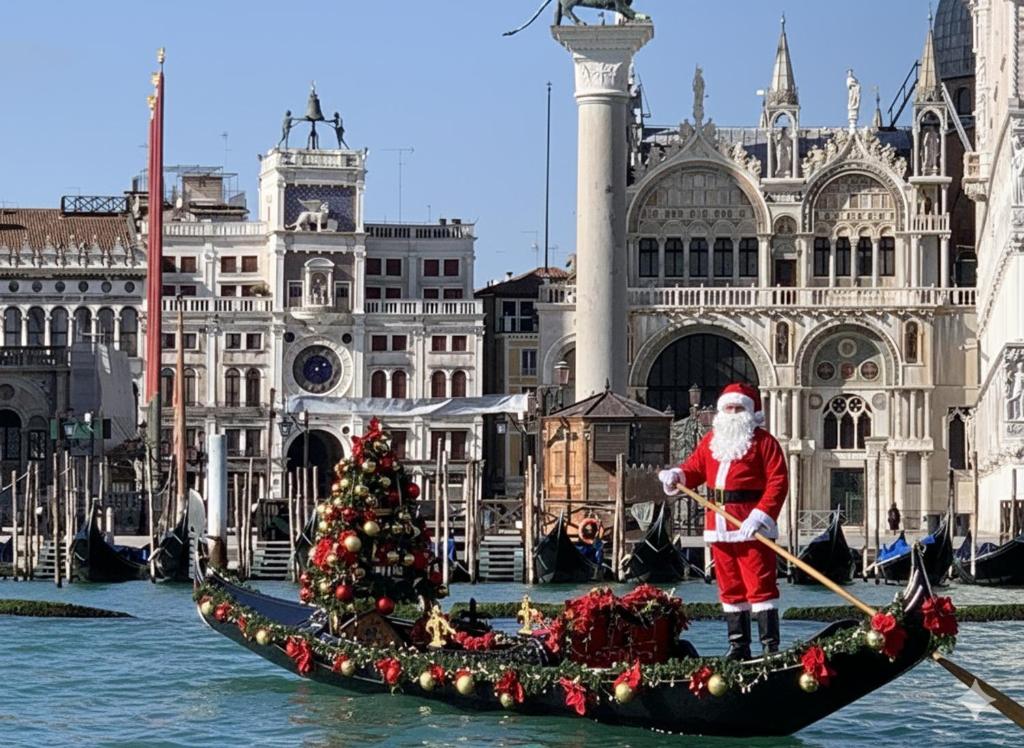 un Babbo Natale sta remando su una barca con un albero di Natale di Lovenice Center Royalclass a Venezia