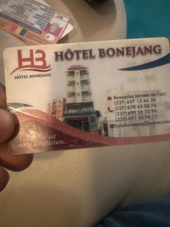 Die Hand einer Person, die eine Eintrittskarte für ein Hotelgebäude hält in der Unterkunft Hôtel Bonejang in Douala