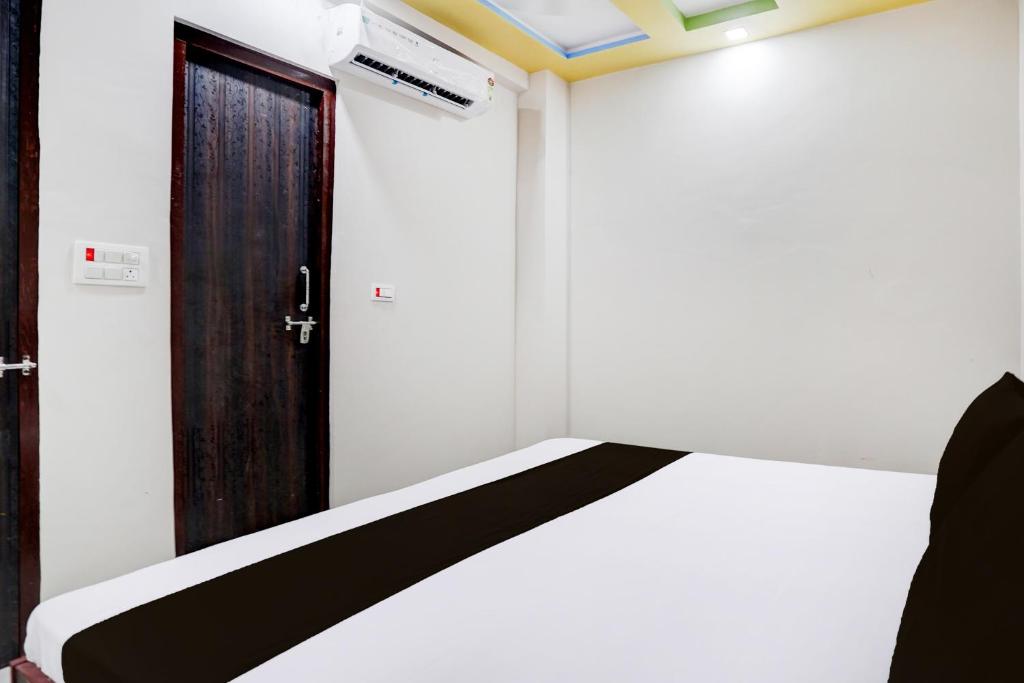 una habitación con una cama con una puerta y una ventana en HOTEL O MAYUR, en Aligarh