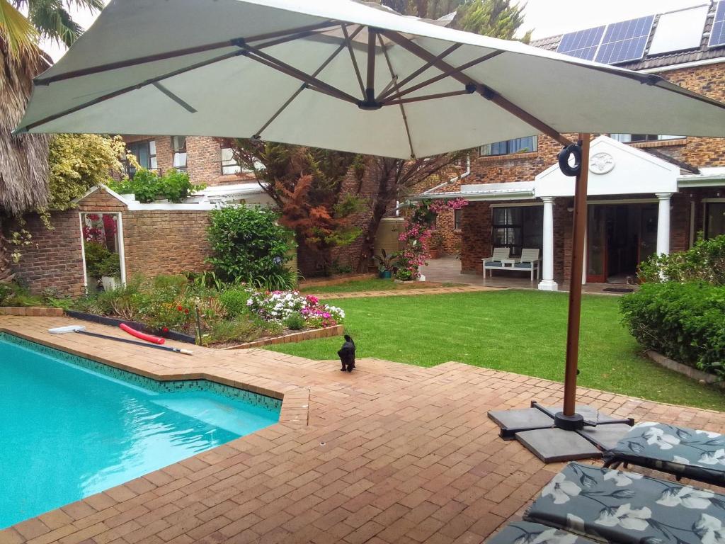 Dressage Guesthouse في Sweet Valley: وجود مظله وكراسي بجانب مسبح