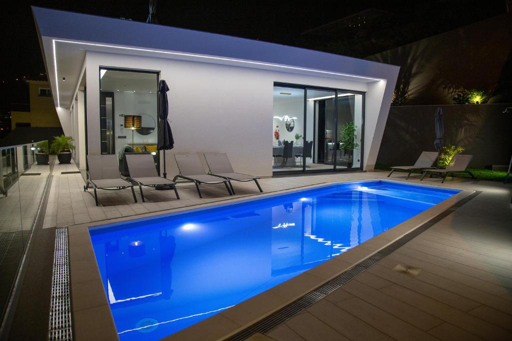 Una piscina en un patio trasero por la noche. en A&M House III, en Arco da Calheta