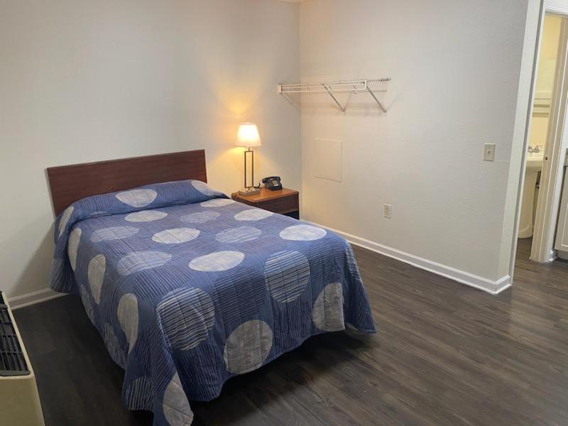 Un dormitorio con una cama y una mesa con una lámpara. en My Town Extended Stay, en Rome