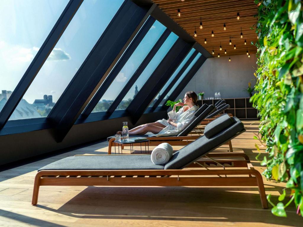 un hombre sentado en una silla en un balcón en The Bridge Wroclaw - MGallery, en Wroclaw