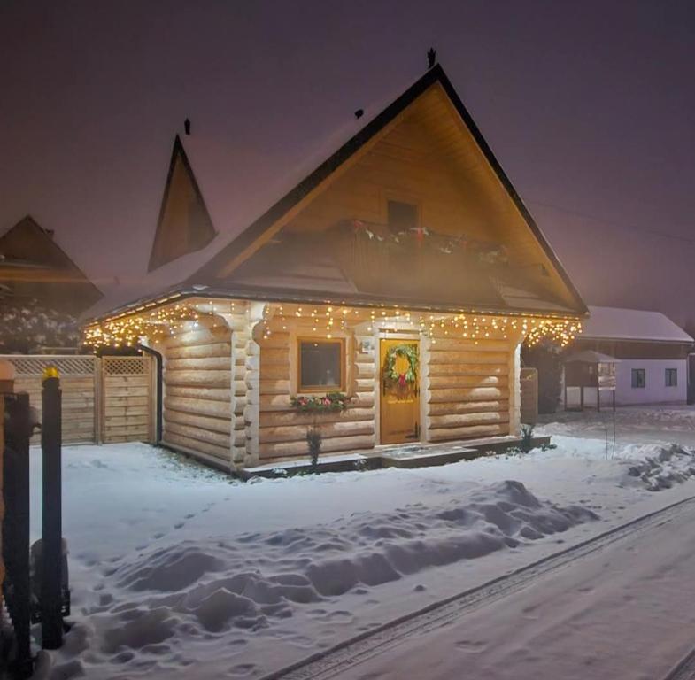 a log cabin covered in christmas lights in the snow at Domek Góralski zakątek Czerwienne in Czerwienne