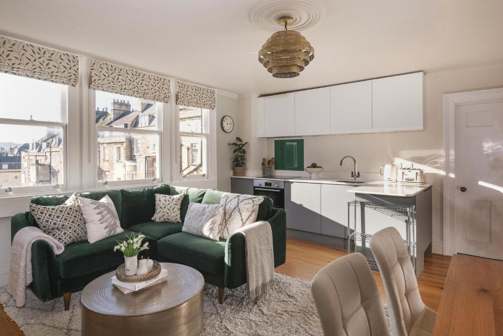 a living room with a green couch and a kitchen at Chic Georgian Escape near Royal Crescent in Bath