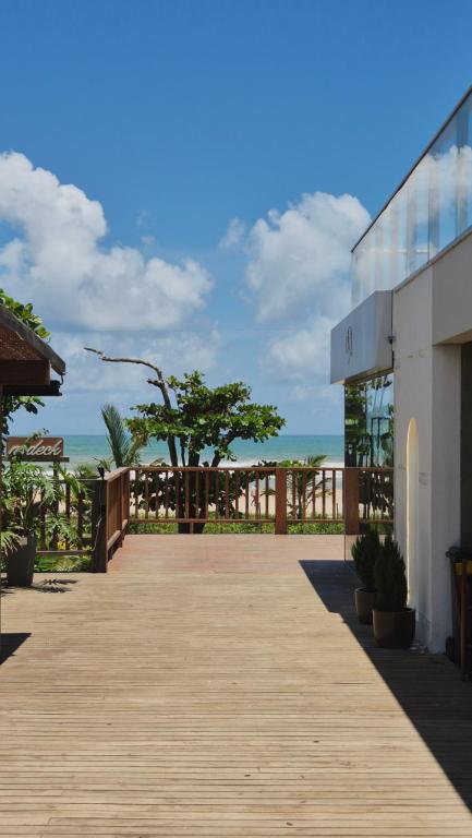 イリェウスにあるApê a 100m do mar com piscina no condomínioの海辺の木造通路付きの建物