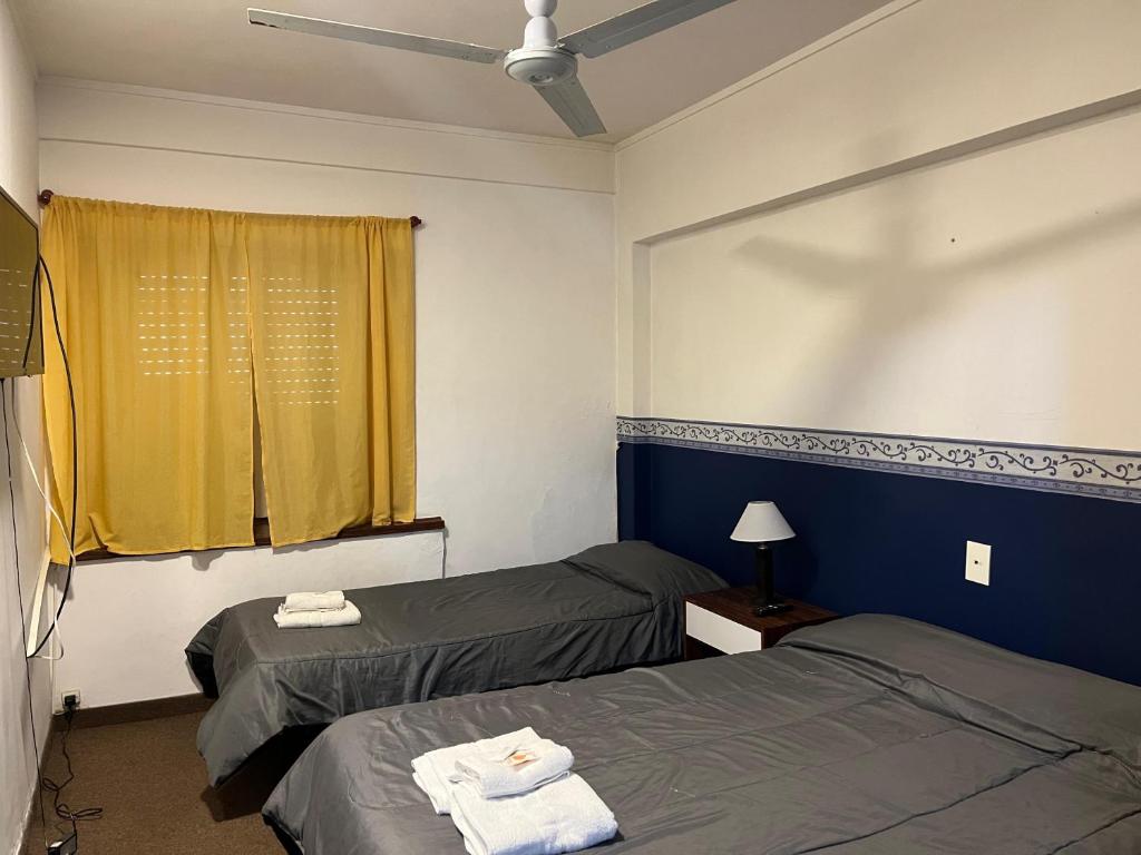 a room with two beds and a yellow curtain at 3Reyes in Necochea