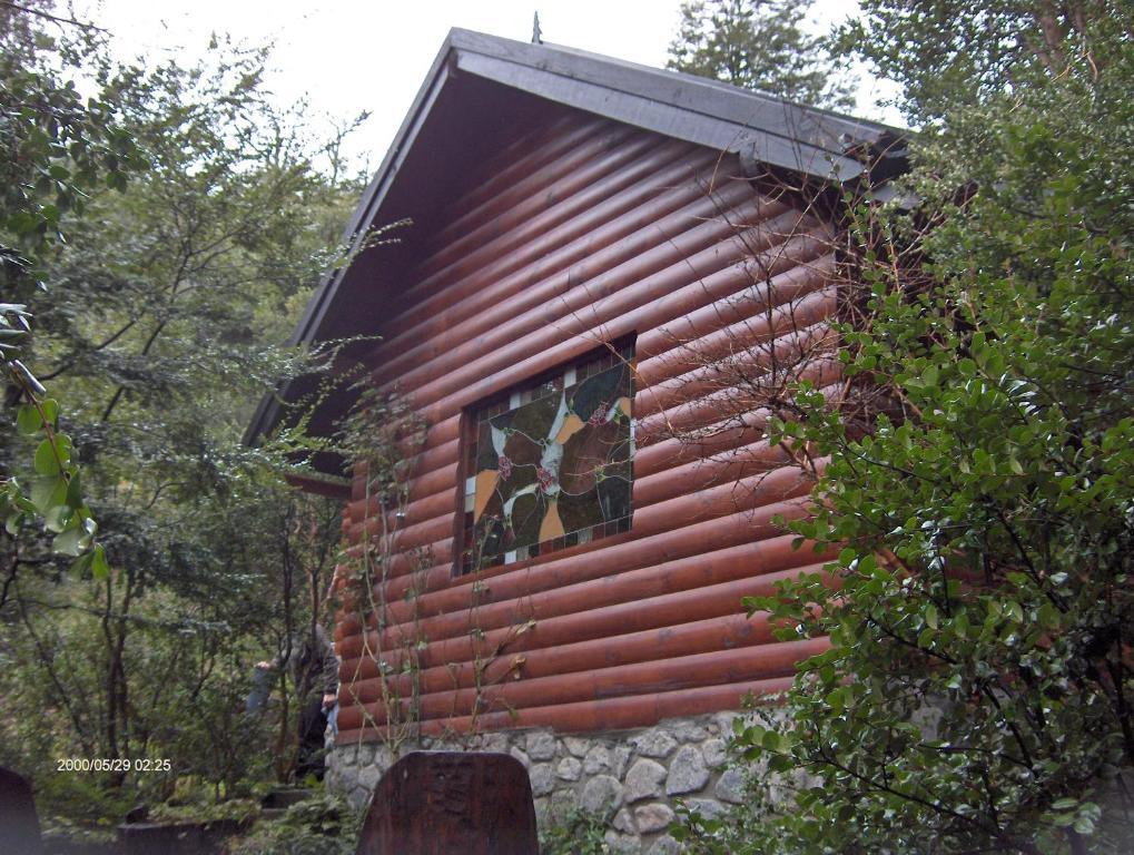 ein kleines rotes Gebäude mit einem Fenster an der Seite in der Unterkunft Cabañas Kalfulafquen in Villa La Angostura