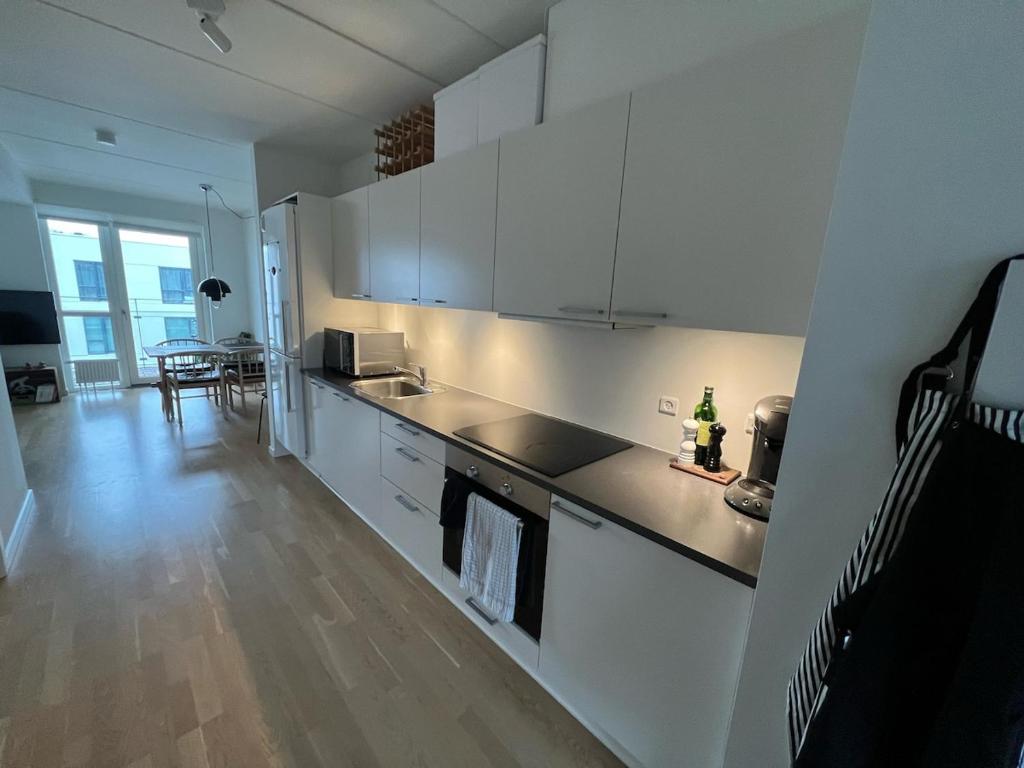 a kitchen with white cabinets and a wooden floor at Odense Habor with access to the harbor sauna and pool in Odense