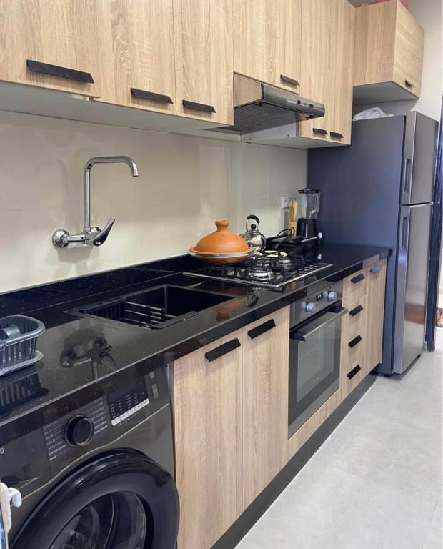 eine Küche mit einem Herd und einer Waschmaschine in der Unterkunft Appartement Calme près du Stade Tamensourt in Oulad Akkou