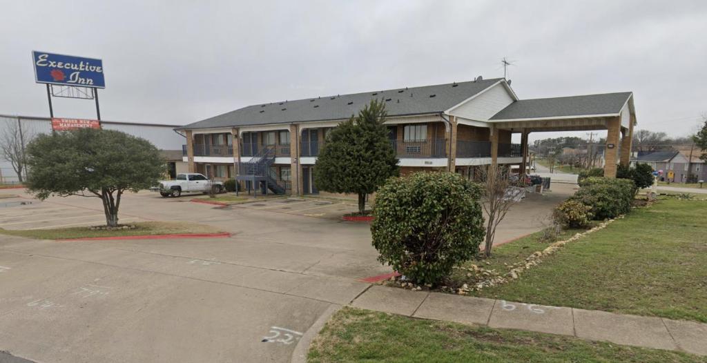 a large building with a sign in front of it at Executive Inn in Fort Worth
