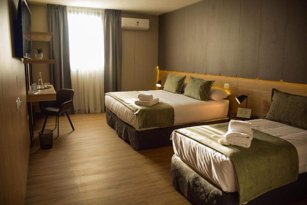 a hotel room with two beds and a desk at Tótem Hotel & Spa in San Martín