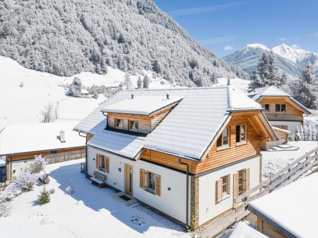 a house in the snow with mountains in the background at Im grünen Herzen in Donnersbachwald