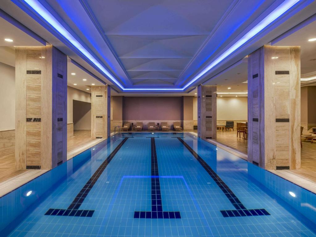 a large indoor swimming pool with blue lighting at Downtown Ankara Hotel in Ankara