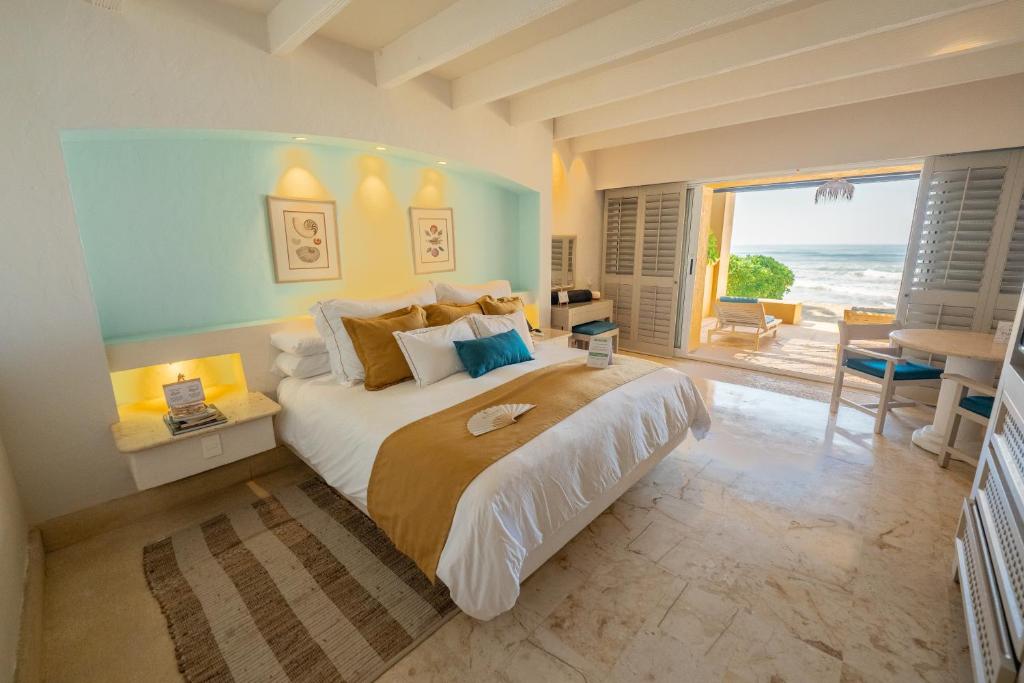 a bedroom with a large bed with a view of the ocean at Hotel Tres Vidas Acapulco in Barra Vieja