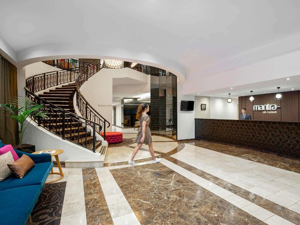 Una mujer caminando por un vestíbulo con una escalera. en Mantra on Russell, en Melbourne