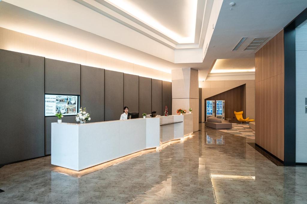 a lobby with a woman standing at a reception desk at lee hotel lat phrao in Bangkok