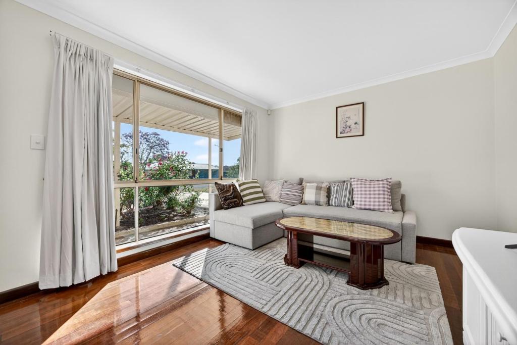 een woonkamer met een bank en een tafel bij Spacious 4-Bed House with Private Garage in Coodanup
