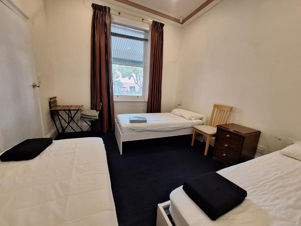 a small room with two beds and a window at Adelaide Free Souls in Adelaide