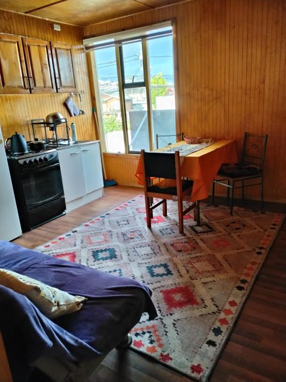 a living room with a table and a kitchen at Departamento centro Quellon in Quellón