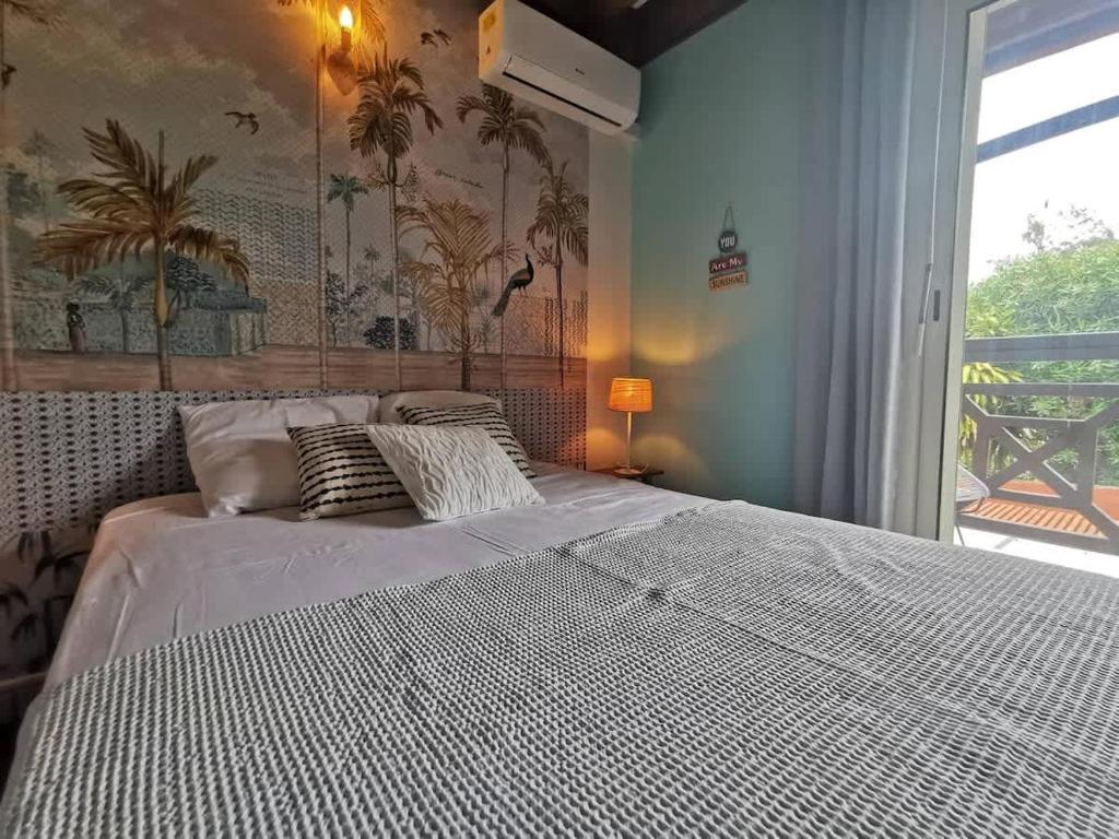 COTTAGE BLUE classé 3 étoiles - 4 à 6 personnes - 2 chambres - accès direct à la plage et à l'esplanade de Boucan Canot avec ses bars et restaurants في سان جيل لي بان: غرفة نوم بسرير أبيض مع نافذة كبيرة