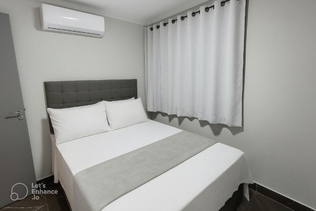 een wit bed in een kamer met een raam bij Apto elegante no Catolé 301 in Campina Grande
