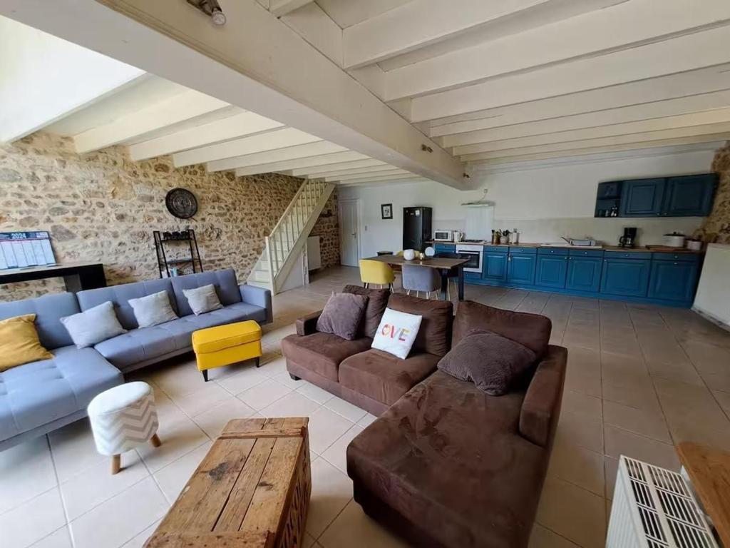 a living room with couches and a table and a kitchen at Gîte de Charme avec Jardin, Wifi et Parking à Saint-Gourson - FR-1-653-285 in Saint-Gourson