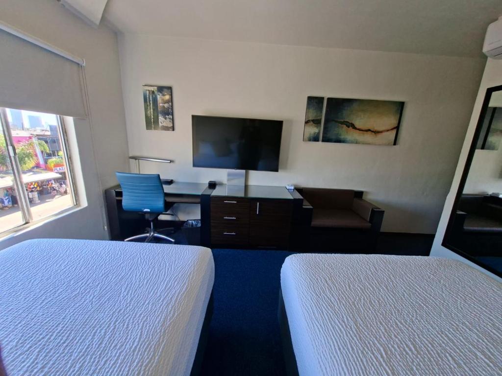 a hotel room with two beds and a desk and a tv at Hotel Nelson in Tijuana