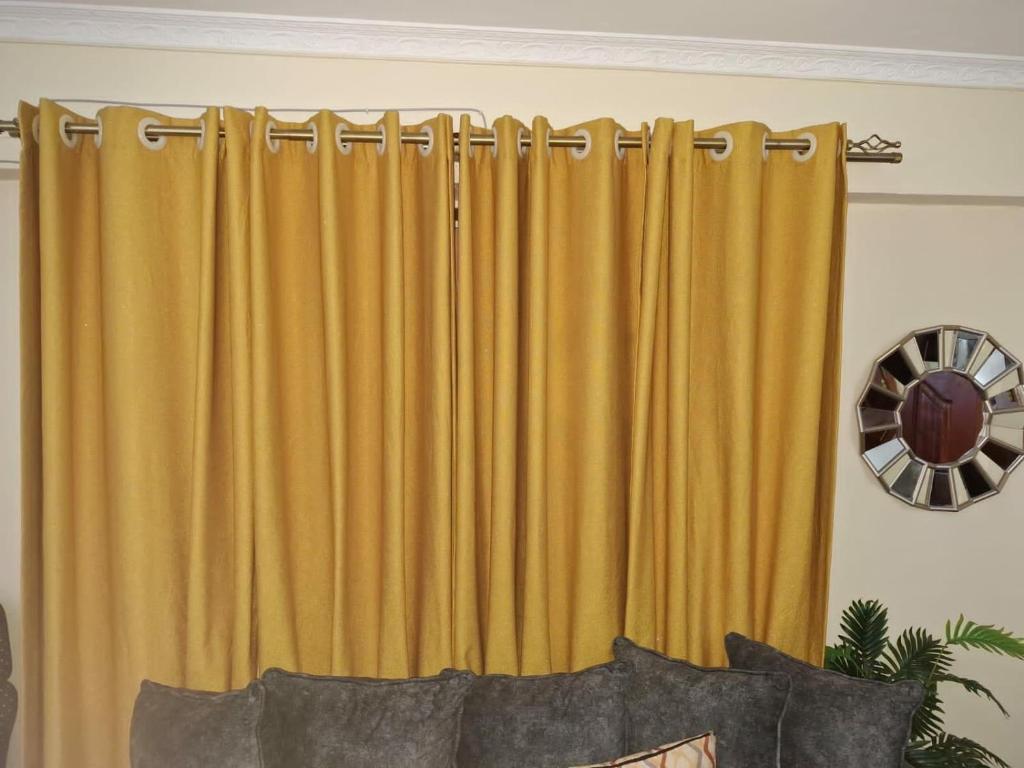 MeruZayana staycation的房间里挂着黄色窗帘，房间里有一张沙发。