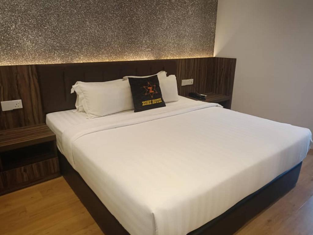 Una cama blanca con un libro encima. en Zone Hotel Ipoh, en Ipoh