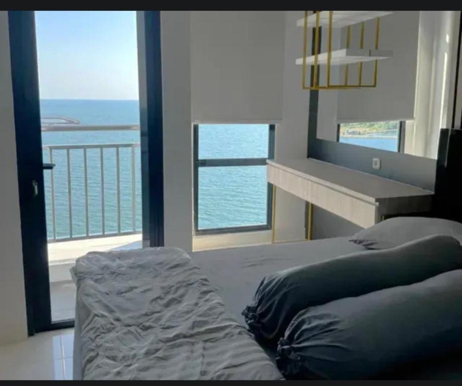Delft Apartement Sunset CPI Makassar في Tanjungbunga: غرفة نوم مع سرير وإطلالة على المحيط