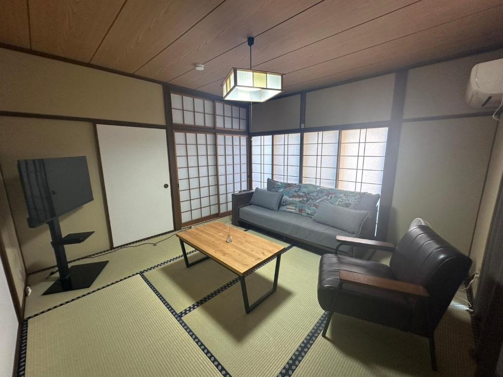 ein Wohnzimmer mit Sofa und Tisch in der Unterkunft MIYABI stay house in Tamana