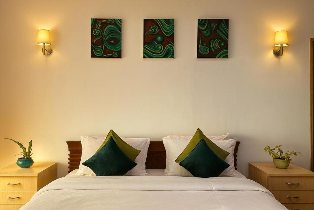 een slaapkamer met een bed met vier schilderijen aan de muur bij Secret Escape Heritage Bungalow in Ooty