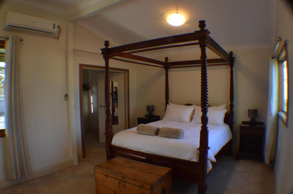 a bedroom with a wooden canopy bed with a wooden trunk at Norseman AirbnbAngels Place in Norseman